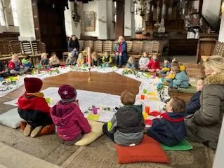 Mehrere Kinder sitzen um einen Tisch mit Bastelutensilien.