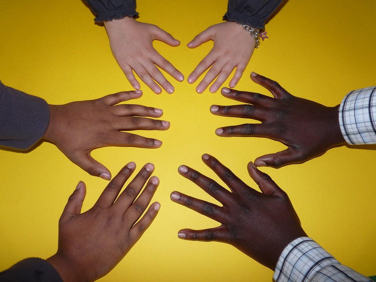 Sechs zueinander gehaltene Hände in verschiedenen Hautfarben.
