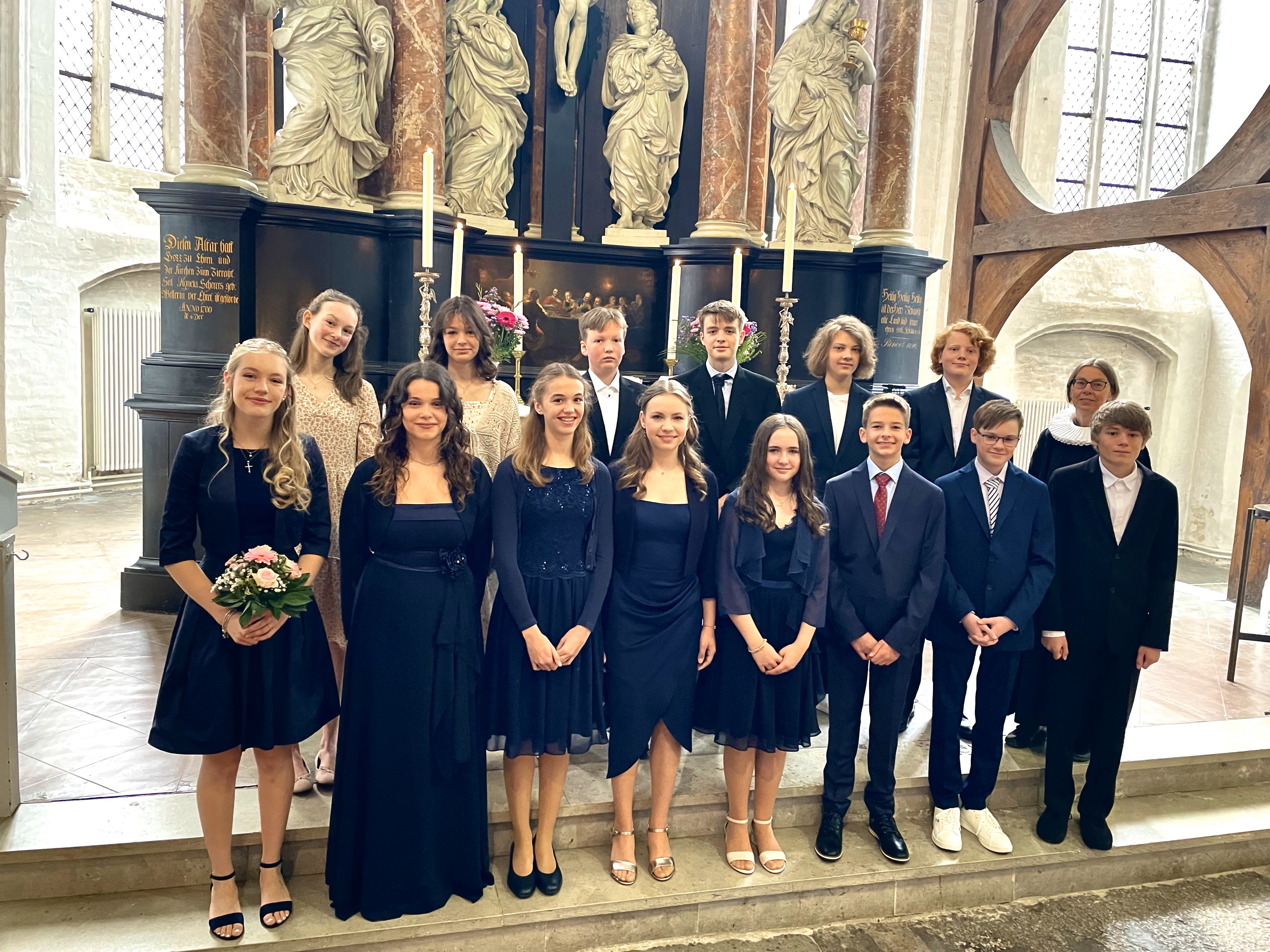 Ein Gruppenfoto von Konfirmanden vor dem Altar in St. Aegidien, umrahmt von Pastorin Nicola Nehmzow und dem damaligen Vikar Tobias Knöller